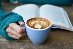 Girl drinking coffee while reading a book